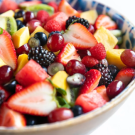 A close up of a bowl of fruits including strawberries, blueberries, blackberries, kiwi, grapes, and more. 