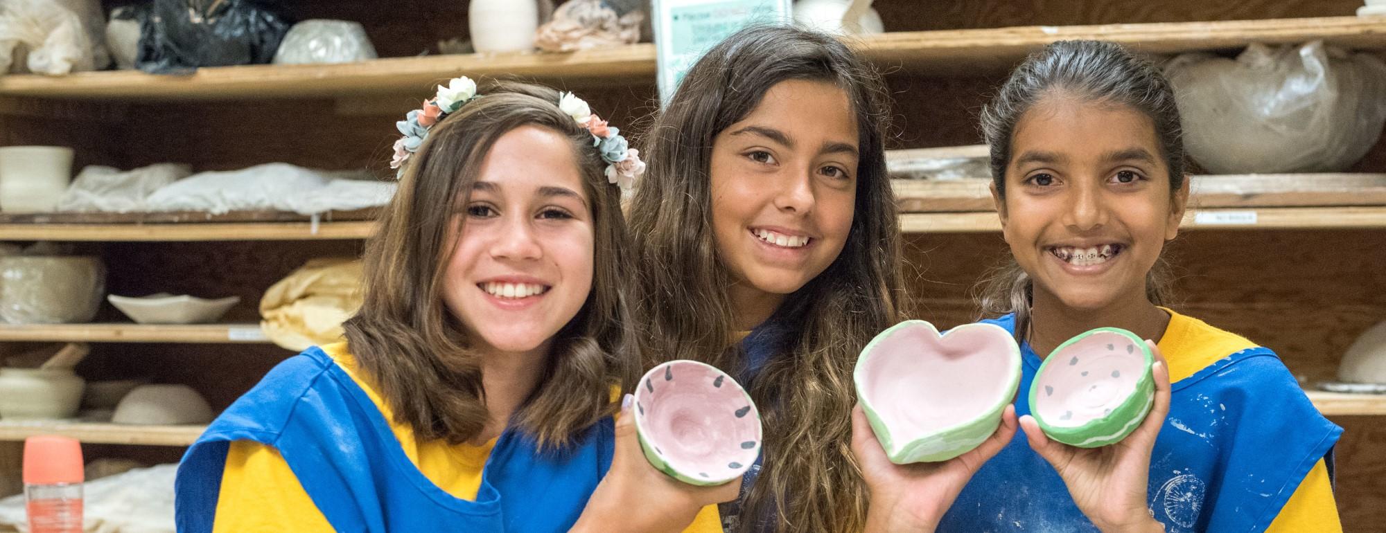 Girls sharing the bowls they made in a Youth Program class.